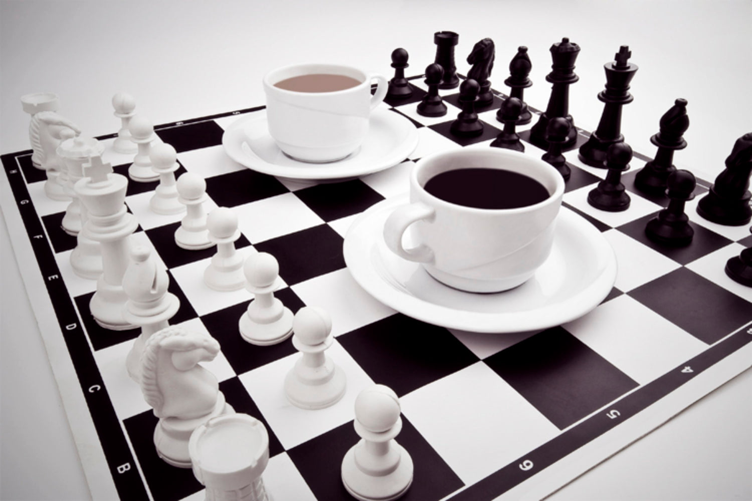 A chess board with two cups of coffee in the middle