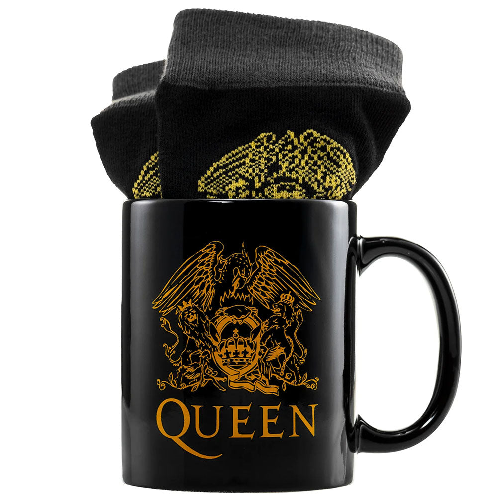 A black mug with the queen logo in gold and a pair of black socks with the same gold logo in the top of the mug